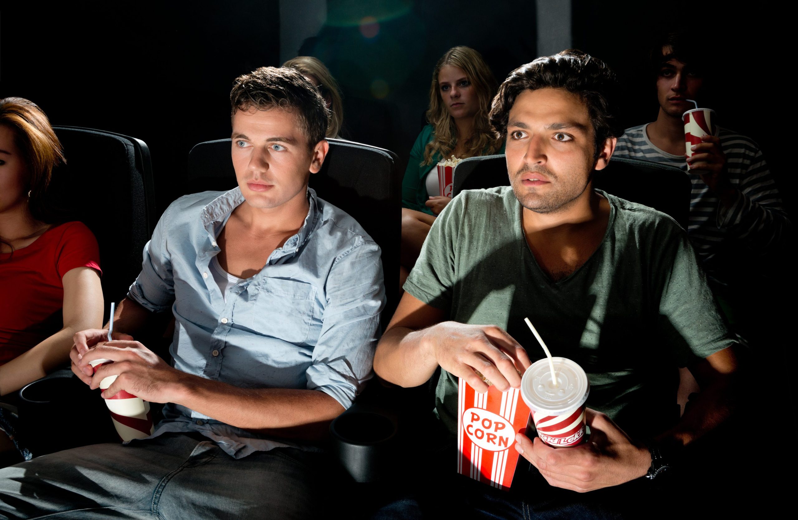 Friends watch a movie. Парень в кинотеатре. Два друга в кинотеатре. Друзья сидят в кинотеатре. Два парня в кинотеатре.